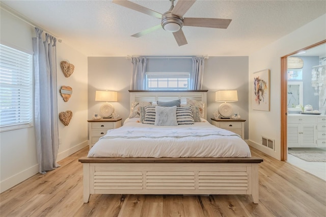 bedroom featuring ceiling fan, connected bathroom, light wood-type flooring, and a textured ceiling