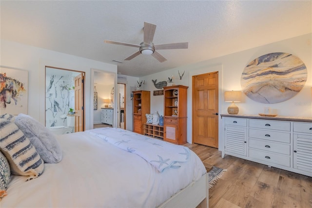 bedroom featuring light wood-type flooring, a textured ceiling, ceiling fan, and ensuite bathroom