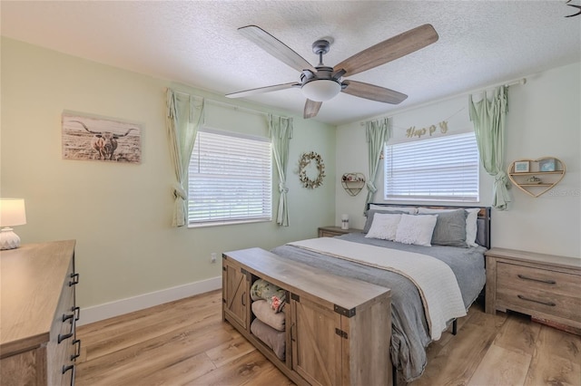 bedroom with a textured ceiling, light wood-type flooring, and ceiling fan