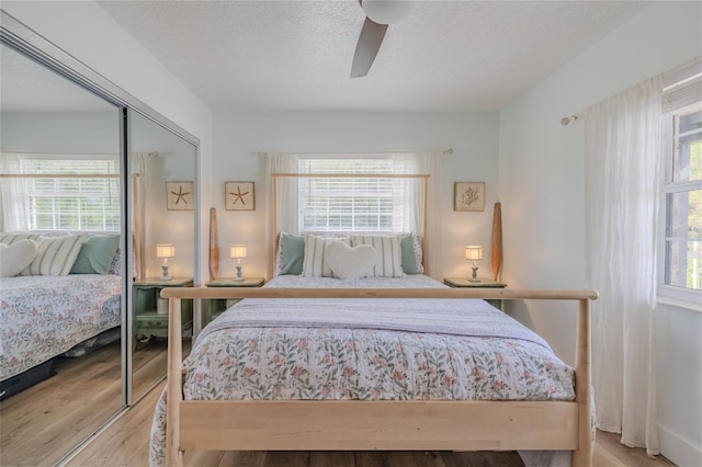 bedroom featuring multiple windows, light hardwood / wood-style floors, ceiling fan, and a closet