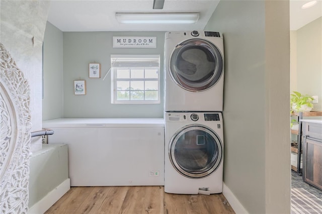 clothes washing area featuring light hardwood / wood-style flooring and stacked washer / drying machine