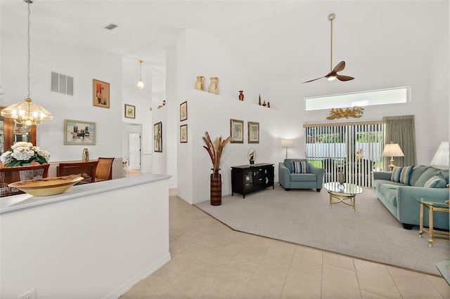 tiled living room with ceiling fan with notable chandelier and high vaulted ceiling