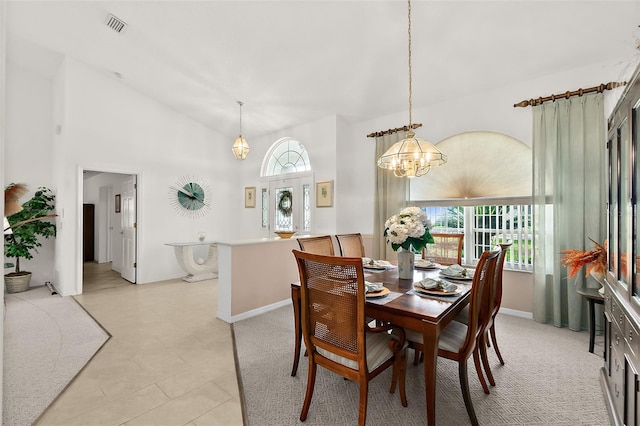 dining area with light tile patterned floors, an inviting chandelier, and high vaulted ceiling