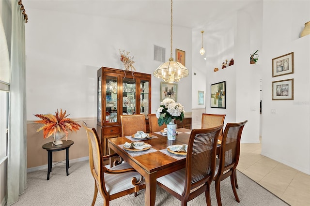 tiled dining area featuring high vaulted ceiling and a notable chandelier