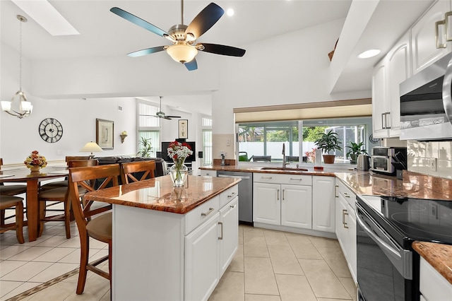 kitchen featuring white cabinets, a breakfast bar area, light tile patterned floors, and stainless steel appliances