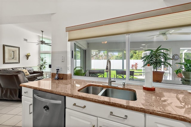 kitchen with stainless steel dishwasher, sink, light stone countertops, and white cabinets