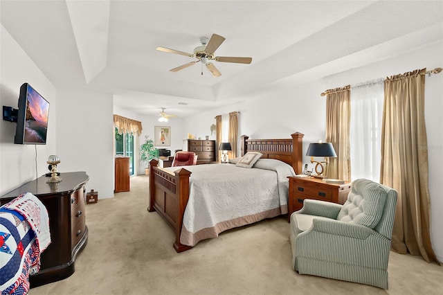 carpeted bedroom with ceiling fan and a raised ceiling