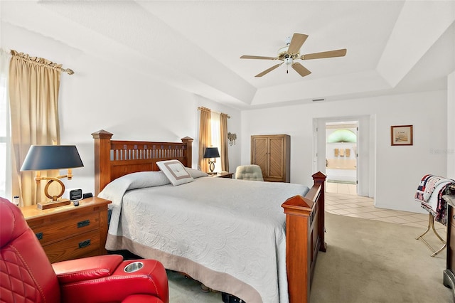 bedroom featuring ensuite bath, light colored carpet, ceiling fan, and a raised ceiling