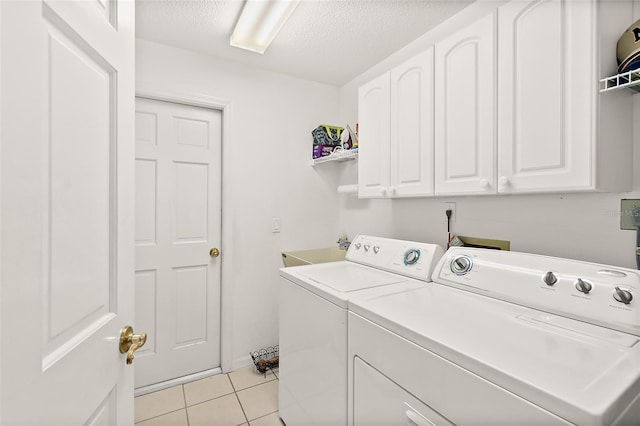 washroom featuring cabinets, sink, a textured ceiling, light tile patterned floors, and washer and clothes dryer