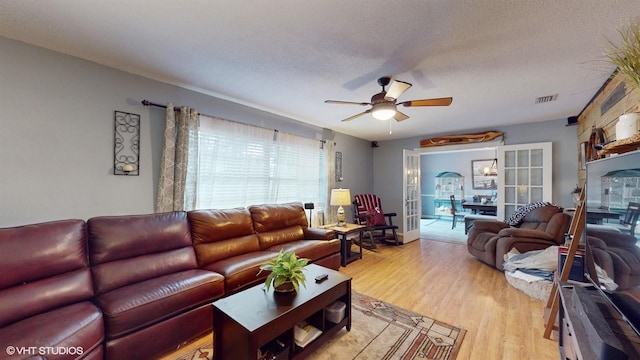 living room with a textured ceiling, french doors, light hardwood / wood-style flooring, and ceiling fan