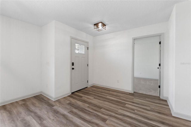 entryway with a textured ceiling, baseboards, and wood finished floors