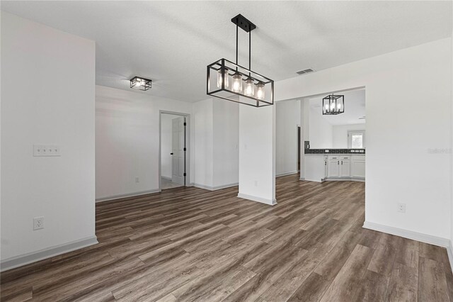 unfurnished dining area featuring dark wood-type flooring, visible vents, and baseboards