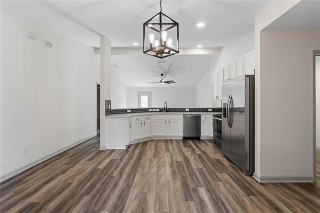 kitchen with dark wood finished floors, appliances with stainless steel finishes, white cabinets, vaulted ceiling, and a sink