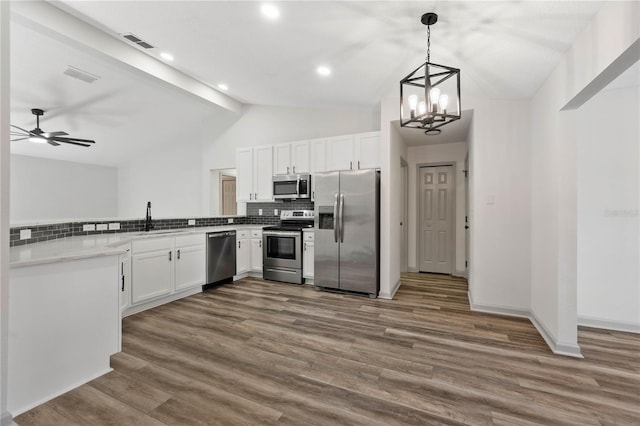 kitchen with dark wood-style flooring, stainless steel appliances, lofted ceiling, visible vents, and backsplash