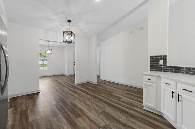 unfurnished dining area with baseboards, a chandelier, and dark wood-type flooring