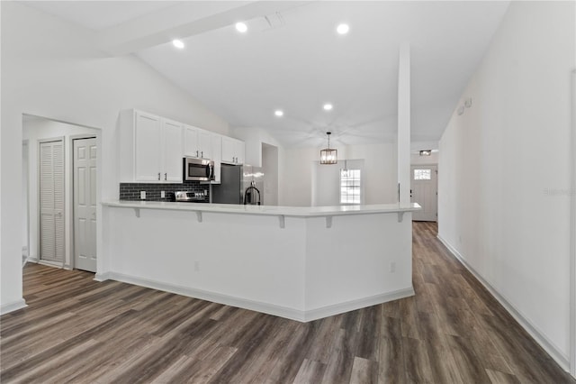 kitchen with appliances with stainless steel finishes, dark wood-style flooring, vaulted ceiling with beams, a peninsula, and white cabinetry