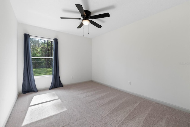 carpeted empty room featuring a ceiling fan and baseboards