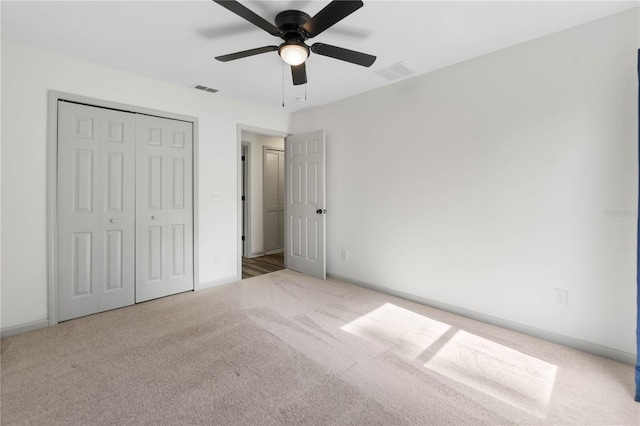 unfurnished bedroom with carpet floors, a ceiling fan, visible vents, and a closet