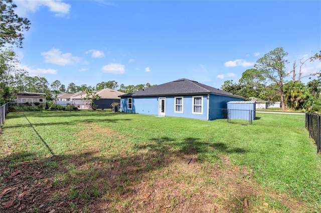 back of house with a yard, a fenced backyard, and stucco siding