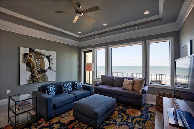 living room featuring a tray ceiling, ceiling fan, and ornamental molding