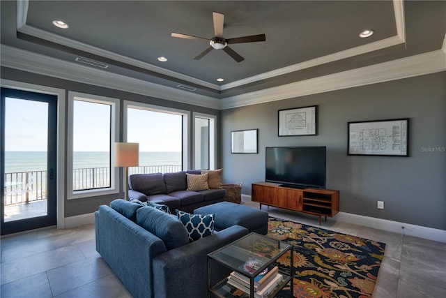 living room with a water view, crown molding, ceiling fan, light tile patterned floors, and a tray ceiling