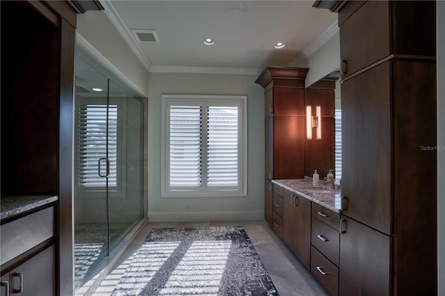 bathroom with vanity, a shower with shower door, and ornamental molding