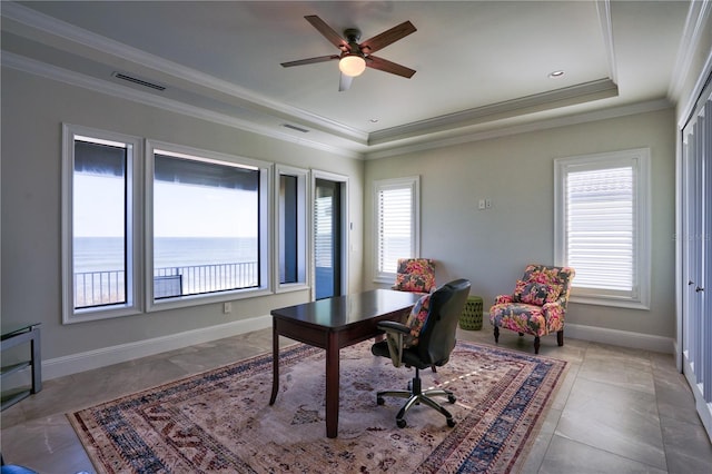 office area featuring a tray ceiling, ceiling fan, a water view, and ornamental molding