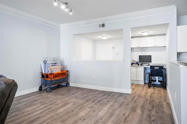 home office with light wood-type flooring, built in desk, and crown molding