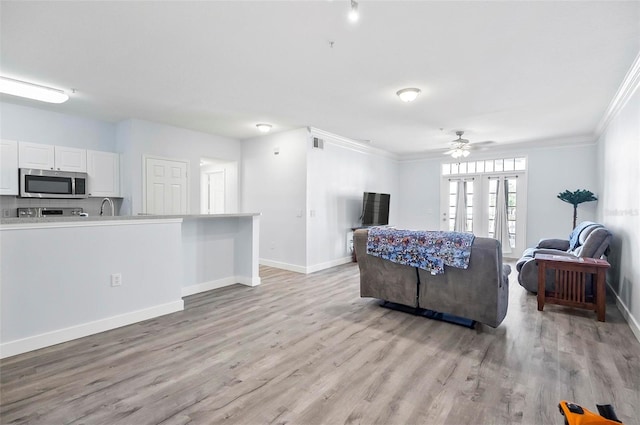 living room featuring light hardwood / wood-style flooring, ceiling fan, crown molding, and sink