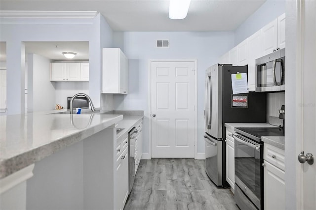 kitchen featuring light hardwood / wood-style floors, sink, light stone countertops, white cabinetry, and appliances with stainless steel finishes