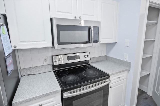 kitchen with white cabinets, appliances with stainless steel finishes, and tasteful backsplash