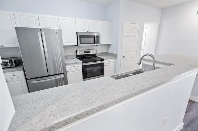 kitchen with stainless steel appliances, dark wood-type flooring, sink, tasteful backsplash, and white cabinetry