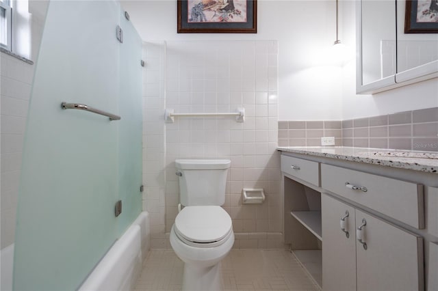 full bathroom featuring tile patterned flooring, toilet, and tile walls