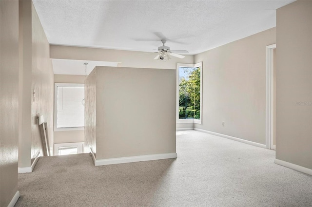 carpeted empty room featuring ceiling fan and a textured ceiling