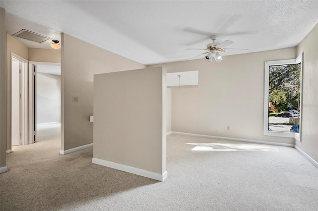 unfurnished room featuring ceiling fan, light carpet, and a textured ceiling