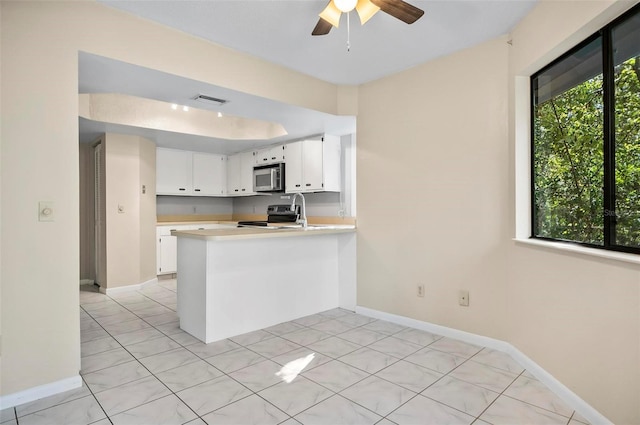 kitchen featuring kitchen peninsula, stainless steel appliances, ceiling fan, light tile patterned floors, and white cabinets