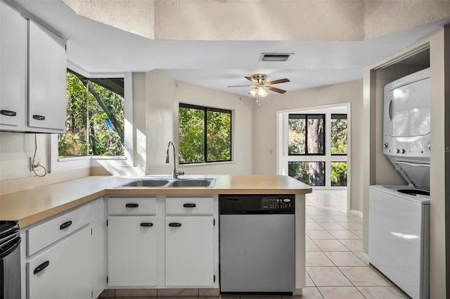 kitchen featuring white cabinets, sink, light tile patterned floors, stacked washer and clothes dryer, and dishwasher