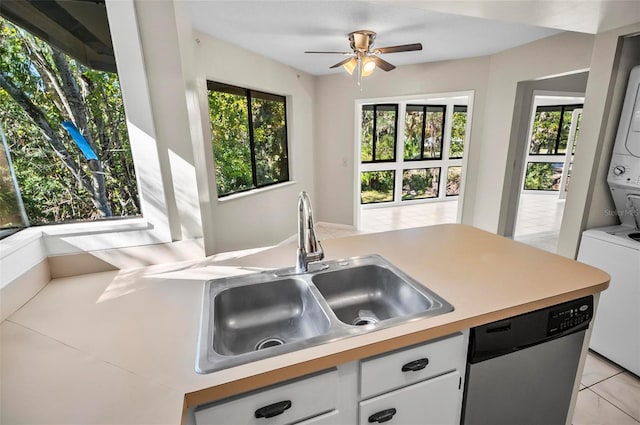 kitchen with dishwasher, stacked washer and clothes dryer, white cabinets, sink, and light tile patterned flooring