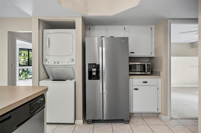 kitchen featuring stacked washing maching and dryer, light colored carpet, white cabinetry, and stainless steel appliances