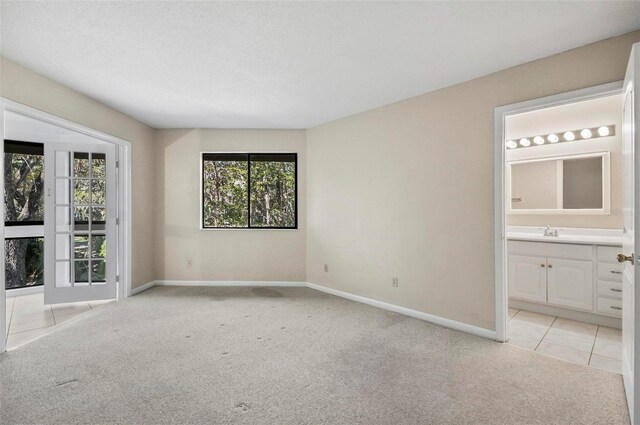 spare room featuring a textured ceiling, sink, and light carpet