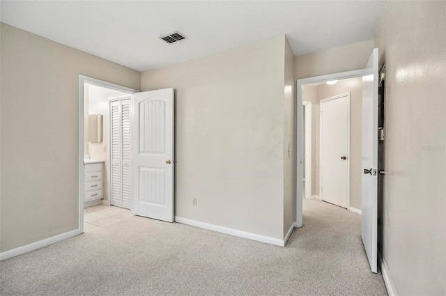 unfurnished bedroom with ensuite bathroom and light colored carpet