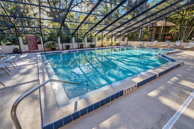 view of swimming pool featuring glass enclosure and a patio