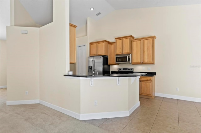 kitchen with stainless steel appliances, light tile patterned floors, high vaulted ceiling, a kitchen breakfast bar, and kitchen peninsula