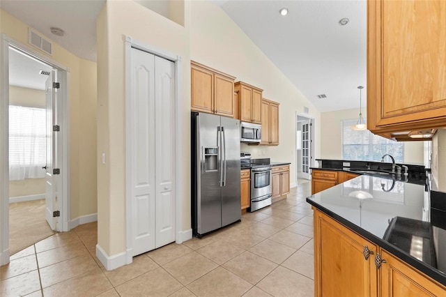 kitchen featuring stainless steel appliances, decorative light fixtures, light tile patterned floors, sink, and vaulted ceiling