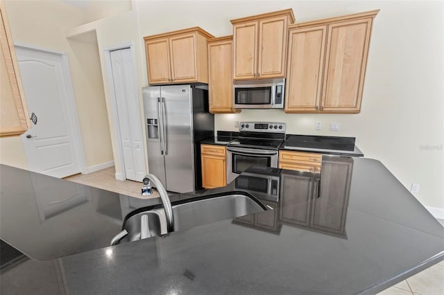 kitchen featuring light brown cabinets, stainless steel appliances, light tile patterned floors, and sink