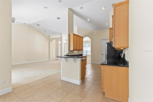 kitchen with a kitchen bar, light colored carpet, lofted ceiling, kitchen peninsula, and stainless steel stove