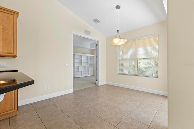 unfurnished dining area with light tile patterned floors and vaulted ceiling