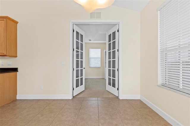 unfurnished dining area featuring french doors, lofted ceiling, and light tile patterned floors