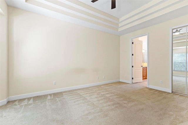 spare room with ceiling fan, light carpet, and a tray ceiling