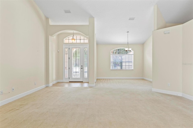 entrance foyer with light colored carpet and a notable chandelier